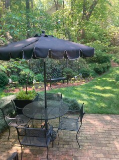 Outdoor garden patio with table, chairs, and large umbrella in Charlotte Garden Club.